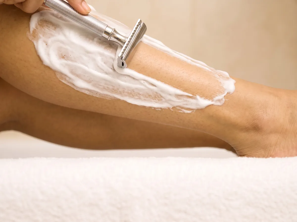 Bikini Laser Hair Removal in Jaipur: Razor bumps along the crease, Shaving: a razor and foam on a shin, close-up | AI Aesthetics, C-Scheme
